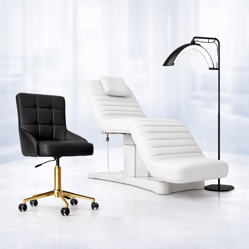Black salon chair with gold base beside white electric beauty bed and floor lamp