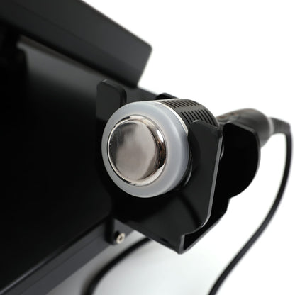 close-up of RF microneedling device handpiece with metal applicator tip securely held in a black cradle mount.