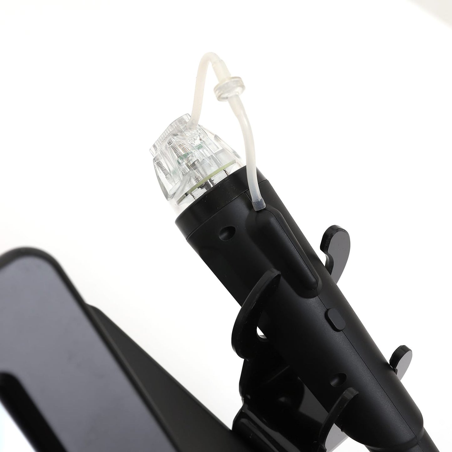 Close-up of mirconeedling handpiece with attached tubing and needle cartridge, resting in a black holder bracket.